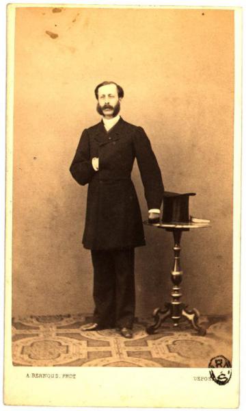 Ritratto maschile - Uomo in piedi con cappello a tuba posato sul tavolo