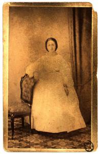 Ritratto femminile - Donna in abito chiaro in piedi appoggiata a una sedia