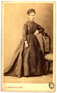 Ritratto femminile - Giovane in abito scuro in piedi appoggiata allo schienale di una sedia
