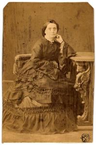 Ritratto femminile - Donna in abito a balze seduta accanto a un tavolo