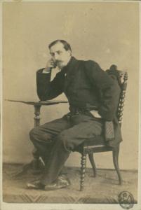 Ritratto maschile - Uomo seduto su una poltrona appoggiato a un tavolo