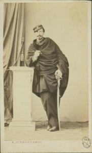Ritratto maschile - Militare - Dederchi ufficiale, in piedi con tabarro e spada, appoggiato a un pedistallo