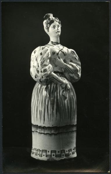 Bari - Raccolta Avv. Maselli. Fiasca in ceramica decorata a forma di donna con abito lungo e maniche a sbuffo della fabbrica di Grottaglie (inizi XIX sec.).