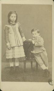 Ritratto di famiglia (?) - Una bambina in piedi accanto ad un bambino seduto (fratelli?)