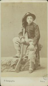 Ritratto maschile - Giovane in abito da bersagliere con un finto fucile, seduto su un masso finto