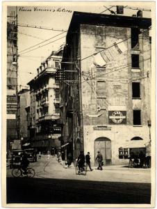 Milano - Via Verziere. Veduta dello slargo di via Verziere angolo via Cerva. Auto, bici e pubblicità del Vov sulla parete di un palazzo.