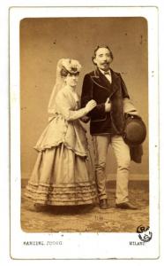 Ritratto di coppia - Donna con cappellino e uomo con soprabito e cappello su un braccio