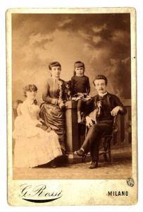 Ritratto di famiglia - Giovane con cane in braccio accanto a due fanciulle e una bambina seduta su una balaustra