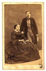 Ritratto di coppia - Donna seduta e uomo in piedi appoggiato allo schienale della sedia