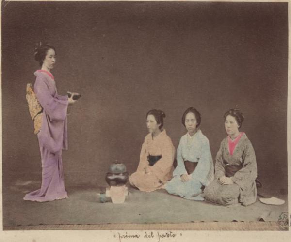 Scena di genere - Una donna, in piedi, vestita con il kimono porta ad altre tre giovani donne giapponesi, sedute, una ciotola di riso - Al centro una teiera sul fornello