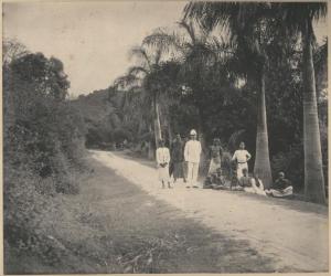 Ritratto di gruppo - Carlo Giussani, quattro uomini e sette bambini su una strada in una foresta tropicale