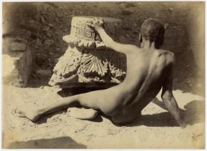 Nudo maschile di schiena seduto a terra, poggiante su un capitello rovesciato