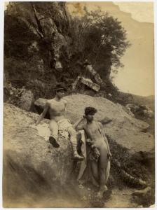 Due nudi maschili drappeggiati, uno in piedi, l'altro seduto. Sullo sfondo, un paesaggio di arbusti e rocce