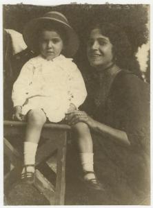 Ritratto di famiglia - Donna inginocchiata a fianco di un bambino seduto con cappello - Esterno