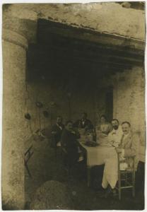 Ritratto di gruppo - Elvira Lazzaroni e Leopoldo Metlicovitz con altri uomini seduti a una tavola imbandita - Pasto - Esterno, porticato rustico