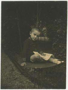 Ritratto infantile - Roberto Metlicovitz seduto su un tavolino con giornale - Esterno, giardino