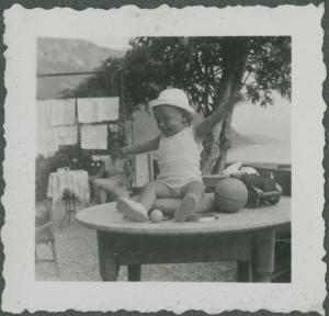 Ritratto infantile - Rita Di Stefano seduta sul tavolo - Giocattoli - Varenna - Casa - Giardino - Lago