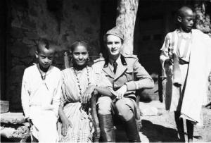 Viaggio in Africa. Insediamento indigeno di Mai Otza - soldato italiano seduto si riposa - al suo fianco un gruppo di indigeni