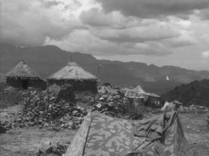 Viaggio in Africa. Paesaggio africano: villaggio di capanne in pietra con tetti di paglia e accampamento militare italiano con tende mimetiche