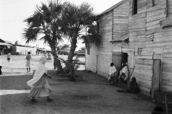 Viaggio in Africa. Massaua: edifici in legno che si affacciano su una strada in terra battuta e palmizi