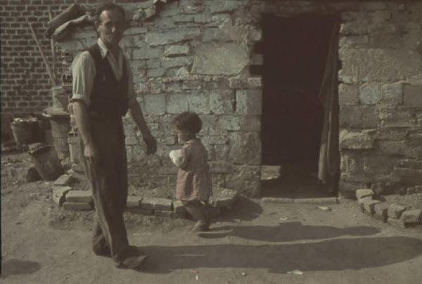 Periferia di Milano: campo nomadi. Ritratto di coppia, uomo adulto e bambino nei pressi di una baracca