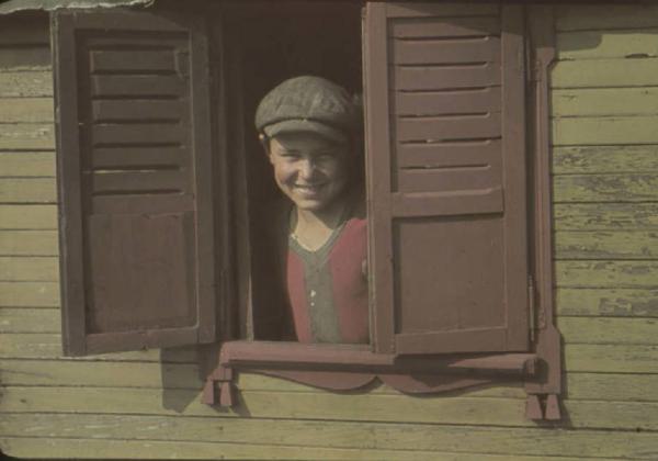 Periferia di Milano: campo nomadi. Ritratto maschile, bambino che si affaccia dalla finestrella di un carro