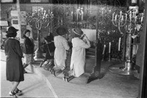 Viaggio in Jugoslavia. Zagabria: donne inginocchiate in preghiera davanti a un tabernacolo di strada ornato con grandi candelabri