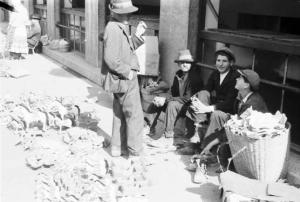 Viaggio in Jugoslavia. Zagabria: il mercato. Uomini croati seduti sul ciglio della strada che vendono manufatti di legno