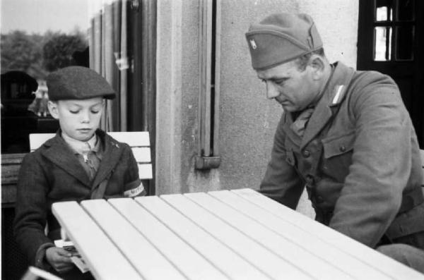 Viaggio in Jugoslavia. Zagabria: miliziano ustascia e giovane recluta seduti al tavolino di un bar