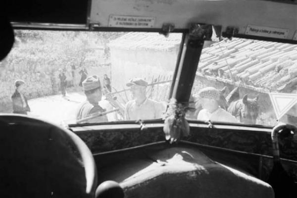 Viaggio in Jugoslavia. Un soldato e contadini croati visti attraverso il parabrezza di un autocarro  militare