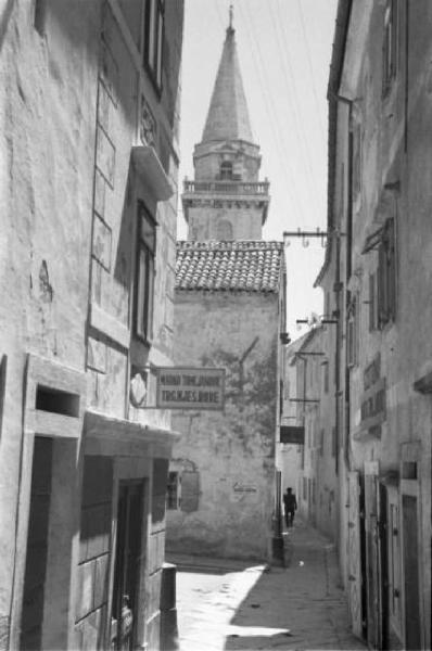 Viaggio in Jugoslavia. Veduta urbana - vicolo su cui affacciano edifici in pietra. Sullo sfondo il campanile di una chiesa