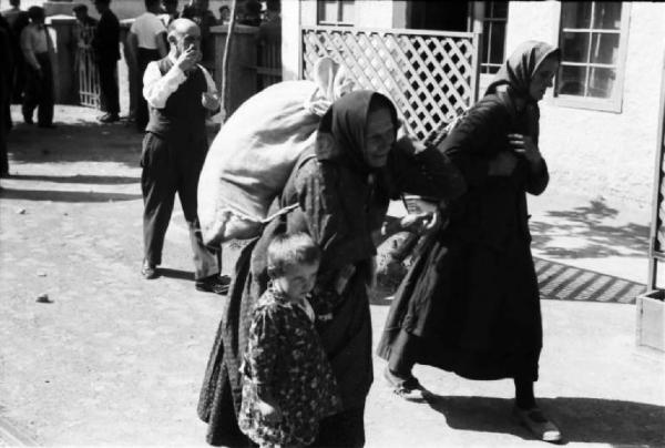 Viaggio in Jugoslavia. Verso Sebenico: madre e figlia in cammino con un sacco sulle spalle