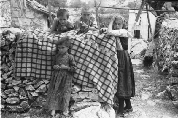 Viaggio in Jugoslavia. Perkovic: fanciulli di famiglia contadina posano nei pressi di una balla di fieno, coperta da una tovaglia a quadri