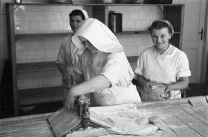 Viaggio in Jugoslavia. Ospedale di Zagabria: le cucine. Suora che stende la pasta sotto lo sguardo di due infermiere