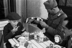 Viaggio in Jugoslavia. Zagabria: miliziano ustascia e una giovane recluta seduti al tavolino di un bar. L'adulto legge la rivista "Tempo"