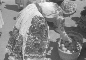 Viaggio in Jugoslavia. Zagabria: donna in abiti tradizionali, in occasione del lunedi di Pentecoste, china su un cesto di frutta