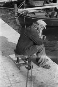 Viaggio in Jugoslavia. Sebenico: un vecchio pescatore seduto sulla banchina del porto