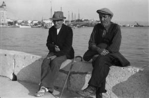 Viaggio in Jugoslavia. Sebenico: coppia di anziani seduti su un muretto nei pressi del porto