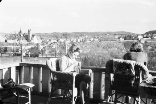 Internamento in Svizzera. Aarau - Laura Patellani cuce seduta in terrazzo in compagnia di Alice - Sullo sfondo la cittadina svizzera