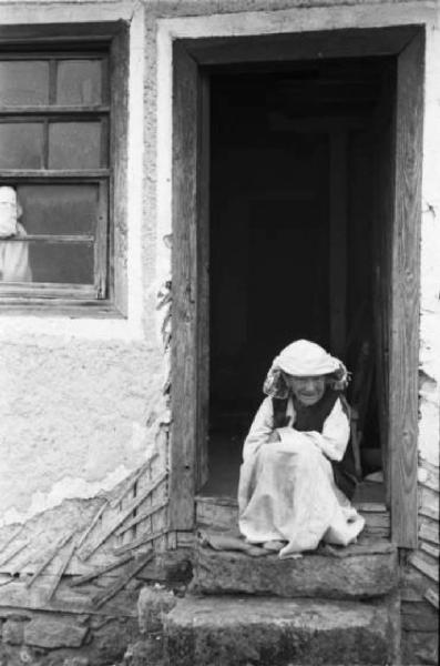 Viaggio in Jugoslavia. Yaitze: anziana abitante seduta sull'uscio della porta di casa