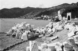 Viaggio in Jugoslavia. Gruz (Gravosa): veduta della costa con blocchi di pietra ammassati sulla spiaggia. Sullo sfondo il paese