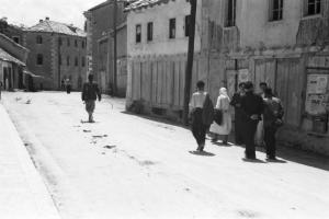 Viaggio in Jugoslavia. Mostar: gruppo di persone cammina lungo una strada del paese