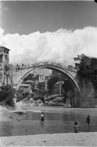 Viaggio in Jugoslavia. Mostar: scene di vita quotidiana - alcuni ragazzi si bagnano nelle acque del fiume Neretva; alle loro spalle il Ponte Vecchio