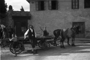 Viaggio in Jugoslavia. Mostar: scene di vita quotidiana - un uomo e un bambino si riposano accanto a un carro trainato da una coppia di cavalli