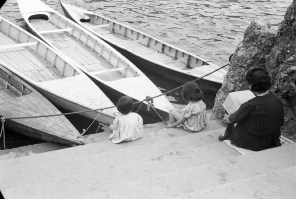 Roma - parco del Valentino. Scorcio nei pressi di un laghetto - di spalle una donna seduta sulla riva di fronte a un gruppo di piccole imbarcazioni ormeggiate