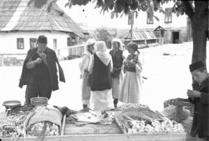 Viaggio in Jugoslavia. Yaitze: un gruppo di giovani donne in costume locale chiacchera sotto un albero, nei pressi di un carretto adibito a trasporto di alimenti - in primo piano si riconoscono un uomo adulto con un fanciullo, a custodia del carretto