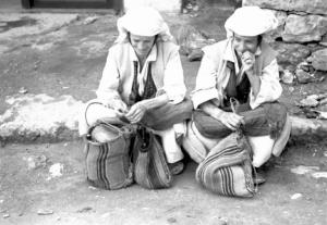 Viaggio in Jugoslavia. Yaitze: coppia di giovani donne bosniache in costume locale sedute su un marciapiede, nella zona del mercato
