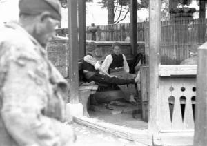 Viaggio in Jugoslavia. Yaitze: scorcio di un gazebo nei pressi del mercato con una coppia di giovani donne bosniache seduta al suo interno - un uomo, in primo piano, le osserva da fuori