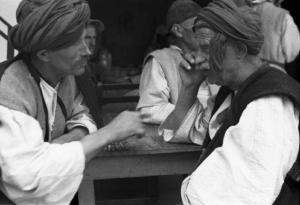 Viaggio in Jugoslavia. Yaitze: coppia di anziani in costume locale discutono seduti al tavolo di un bar