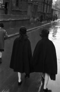 Italia Seconda Guerra Mondiale. Milano - raccolta della lana durante il regime fascista: coppia di Giovani Italiane di spalle durante il tragitto in una via del quartiere